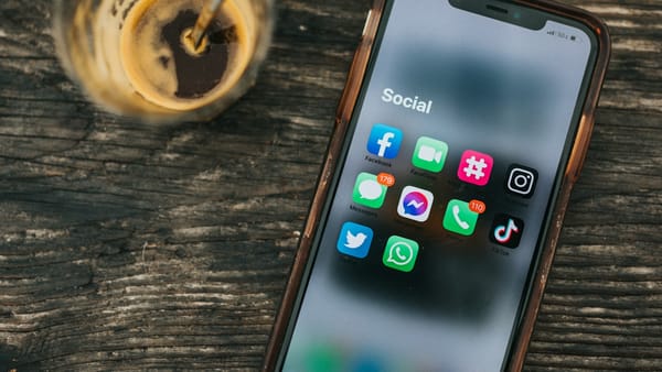 Teléfono móvil con aplicaciones de redes sociales junto a una bebida.